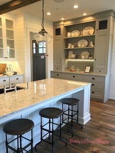 a kitchen island with three stools next to it