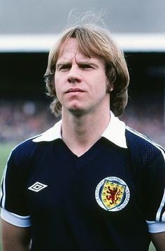 a young man standing on top of a soccer field wearing a black and white shirt