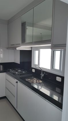 an empty kitchen with black counter tops and white cupboards on either side of the sink