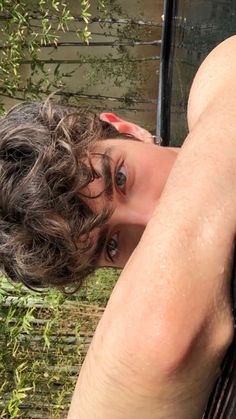 a young man with wet hair leaning against a window