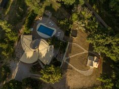 an aerial view of a house with a swimming pool in the middle and trees surrounding it