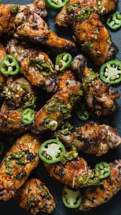 grilled chicken wings with green peppers and jalapenos on a black plate