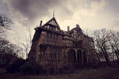 an old abandoned building with vines growing on the roof and in front of dark clouds