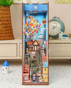 an open cardboard box with a city scene in the middle and balloons floating above it