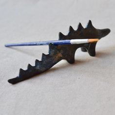 a pencil holder shaped like a dinosaur's tail with a toothpick sticking out of it
