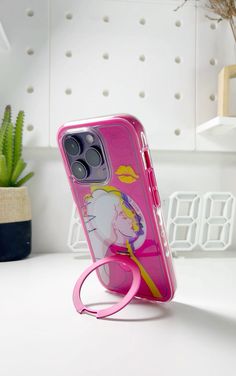 a pink phone case sitting on top of a white table next to a cactus plant