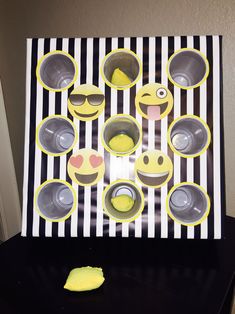 a black and white striped table topped with cups and bowls filled with yellow smiley faces