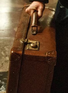 a person holding onto a brown suit case