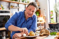 a man sitting at a table with food in front of him and his hands on the plate