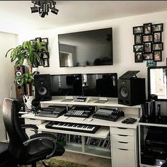 there is a desk with many electronic devices on it and a plant in the corner