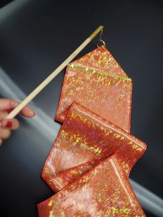 a person holding chopsticks near an origami kite on a black surface