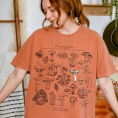 Mycologic Specimens t-shirt designed by Linden & Lichen Studio. The soft vintage wash tee features a variety of vintage mushroom illustrations. Also available in a Comfort Colors sweatshirt! Printed in and shipped from the U.S. Comfort Colors introduces its garment-dyed t-shirt 100% with ring-spun cotton. The soft-washed, garment-dyed fabric brings extra coziness to your wardrobe while the relaxed fit makes it an excellent daily choice. The double-needle stitching throughout the tee makes it hig San Jose, Couture, Vintage Mushroom Illustration, Mushroom Illustrations, Vintage Plants, Comfort Colors Sweatshirt, Vintage Mushroom, Dyed Fabric, Dye T Shirt