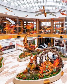 an indoor shopping mall filled with lots of plants and birds flying around the building's atrium