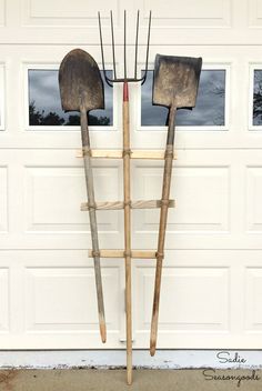 two garden tools are leaning against a garage door