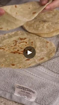 two tortillas sitting on top of a towel next to a person's hand