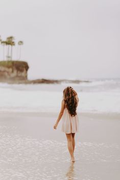 a girl walking on the beach with her back to the camera