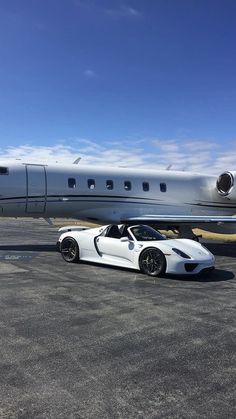 a white sports car parked in front of an airplane