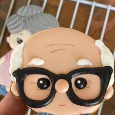 a close up of a person holding a fake doll with glasses on it's head