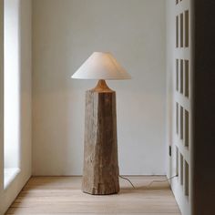 a wooden table lamp sitting on top of a hard wood floor next to a window