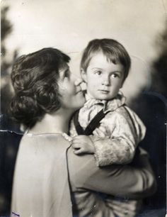 an old black and white photo of a woman holding a young boy in her arms