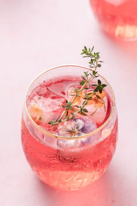 A simple, refreshing, and pretty Pink Lemonade Cocktail. Made with cranberry juice, Malibu, and some fizz to give you a go-to cocktail. Cocktail With Flowers, Summer Floral Party Decor, Cocktails With Edible Flowers, Drinks With Edible Flowers, Petals And Prosecco Theme Outfit, Bridgerton Themed Cocktails, Cocktail Party Food Elegant, Drinks With Flowers, Pink Drinks Alcohol