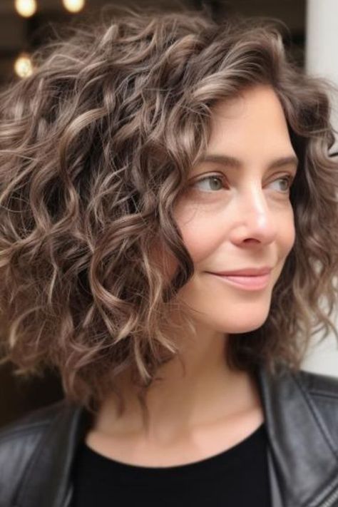 Those who like an edgy and pointy style of hair can adapt to the curly angled lob, which serves as a modification of the classic bob. Such a curly haircut idea for ladies visually stretches the face shape due to its oblique lines. Click here to check out more best curly hairstyles for women over 50. Curly Hair For Over 50 Older Women, Bob Haircut Curly Wavy, Lob Naturally Curly Hair, Short Hair Cuts For Wavy And Curly Hair, Wavy Hairstyles Over 50 Women, Best Hair Styles For Curly Hair, Haircuts For Curly Hair Over 50, Choppy Bob Curly Hair, Styling Shoulder Length Curly Hair