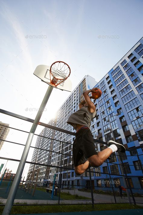 Basketball Player Jumping Action Shot by seventyfourimages. Low angle action shot of African basketball player jumping while shooting slam dunk in outdoor court, copy space #AD #angle, #seventyfourimages, #action, #African Headshot Photography, Low Angle Shot, Basketball Shooting, Basketball Photos, Action Photography, Basketball Photography, Business Headshots, Low Angle, Camera Shots