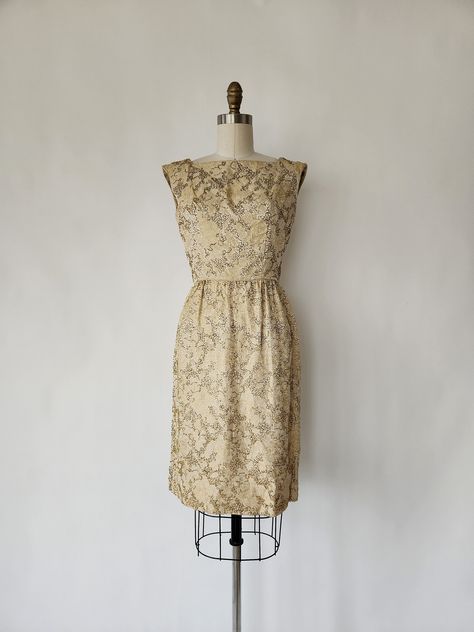 This vintage 1960s gold dust evening cocktail party wiggle dress is sophisticated and lovely. The sleeveless dress features a high square neckline, a darted bodice, pin tucks at the waist, a straight skirt with soft pleating, small gold seed beads and a foral brocade motif throughout and a back metal zipper and clasp closure. A great  dress for the holidays. Also, the perfect little cocktail dress for New Year's Eve. ✂------ M E A S U R E M E N T S ------- best fit: small Dress bust: 34 inches waist: 25 inches hips: 36 inches length: 37 inches tag/label: n/a material: seed beads, brocade thread, and a metal zipper condition: excellent vintage condition ★ Free Shipping - Processing, packaging and tracking are included for most U.S. order and there may be an additional cost for international