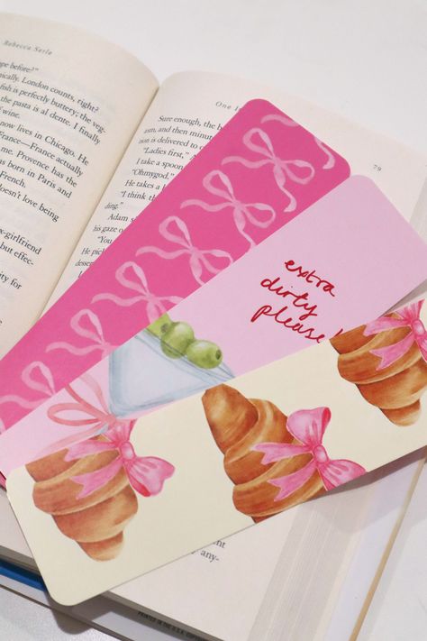 "Introducing our adorable Coquette Styled Bookmark Set of 3! These bookmarks are not only cute but also built to last. With a UV coated, high gloss finish, they are designed to withstand daily use without losing their charm. Measuring 7.25\" x 2\" and made of sturdy card stock, these bookmarks are the perfect companions for your favorite books. Keep your place in style with this delightful set! *Please note, 1 of the bookmarks were printed on 12pt card stock. The other 2 were printed on 14 pt card stock." Cute Books For School, Crafts For Small Business, Bookmark Designs Drawing, Bookmark Diy Aesthetic, Cute Bookmark Designs, Easy Teen Crafts, Cute Binder Ideas, Diy Cute Bookmarks, Colored Paper Crafts