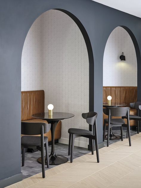 Leather banquette seating within an arch. Small round black table in front with two black chairs. Tiled floor outside of the arch and Bolon inside. Arch Booth Seating, Office With Arches, Arch Interior Design Restaurant, Arch Office Interior, Wall Booth Seating, Office Booth Seating Design, Seating Booth Design, Wall Seating Design, Booth Seating Cafe