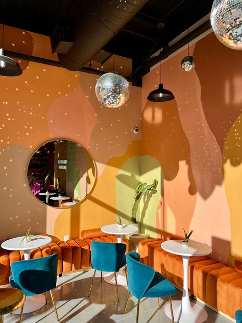 Funky Reception Area, Orange And Green Accent Wall, Groovy Cafe Aesthetic, Quirky Cafe Ideas, Funky Cafe Interior Design, Dispensary Design Interiors, Funky Cafe Design, Colourful Cafe Interior Design, Salon Interior Design Colorful