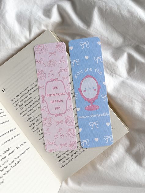 🏹 Girly girl style bookmarks for book lovers  🎀 She romantised her own life and you're the main character bookmarks 🫶 Can be purchased as set or on its own! Bookmark Details: - Bookmark dimensions: 19cm x 5.5cm (approx) - Printed in London on 300gsm textured matte card stock - Bookmarks are available with and without tassels  - Tassel colours varies - Curved edge detail - Blank at the back How To Order: - Select between with or without a tassel!  Shipping Details UK: As our products are made Cute Diy Book Marks, Fancy Bookmarks, Bookmarks Aesthetic, Bookmark Dimensions, Reading Slump, Cute Bookmark, Bookmarks For Books, Cute Bookmarks, Bullet Journal Design Ideas