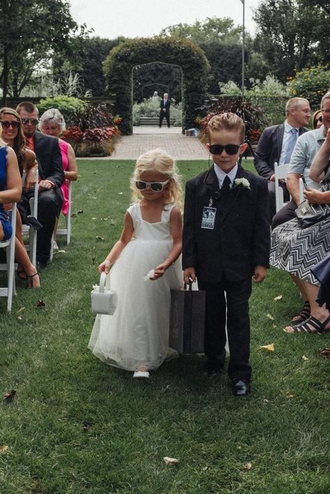 This adorable flower girl rocked cute white sunglasses. The ring bearer wore an adorable "security guard" look with a briefcase, sunglasses, and security tag. Twin Flower Girl And Ring Bearer, Secret Service Ring Bearer, Ring Bearer Aesthetic, 2 Ring Bearers, Ring Bearer Security Guard, Ring Girl Wedding, Wedding Ring Barrier Ideas, Flower Girl And Ring Bearer Ideas, Flower Boy Wedding