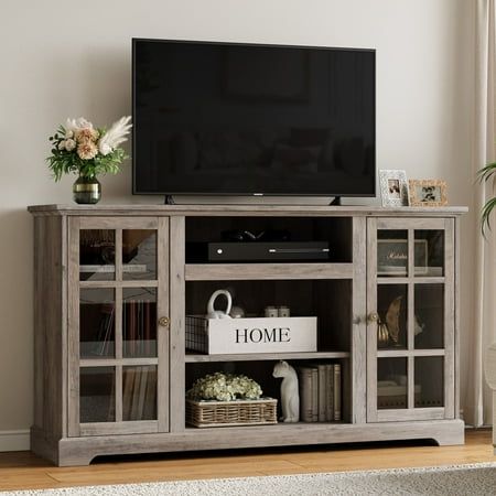 Relefree Modern Farmhouse TV Stand with Glass Door, Entertainment Center Tall TV Console for 65 inch TV, Gray A farmhouse-inspired TV stand with a modern design. Sports a trendy white finish and double wood glass doors blends well with contemporary and farmhouse decor styles. Windowpane-style tempered glass cabinet doors give this entertainment center a decorative touch while enhancing child safety. For flat curved screen TVs up to 65". Five adjustable shelves for flexible to use to hold your electronics, books, photo frames, and more. Both assemble manual and assemble video provide instruction. Bring that modern and rustic feeling to your living room or family area with the TV Stand. Size: 58inchL x 15.9inchD x 29.5inchH.. Gray Tv Console, Entertainment Center With Windows, Tall Tv Stand Ideas, Large Tv Stand Ideas For Living Room, Tv Stand Ideas For Living Room Modern, 65 Inch Tv Stand Ideas, Farmhouse Tv Stand Decor Ideas, Entertainment Center Decor Ideas, Tall Tv Console