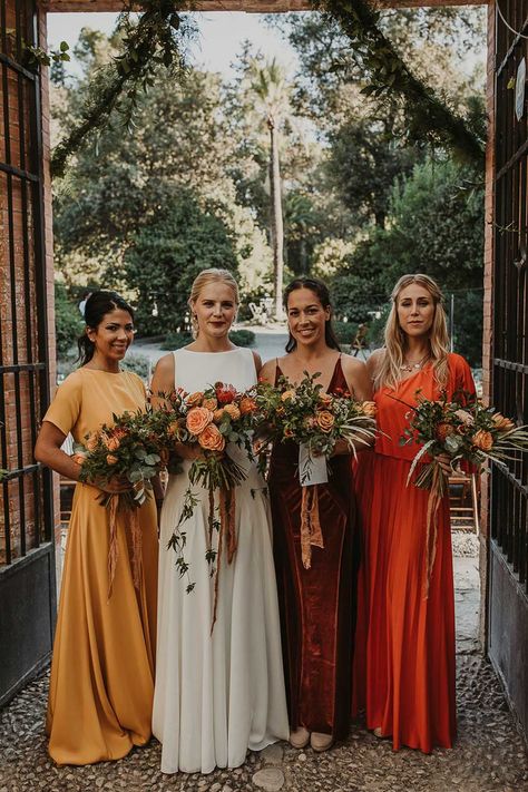 The bridesmaids in yellow, red, and orange bridesmaid dresses smiling for autumn wedding with the bride