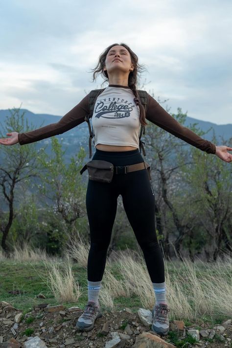 Woman stands with arms outstretched, eyes closed, enjoying the peace of a mountainous landscape at dusk. Camping Leggings Outfit, Hipster Camping Outfit, Camping Women Outfits, Feminine Camping Outfit, Camping Girl Outfit, All Black Hiking Outfit, Legging Hiking Outfit, Outdoor Outfit Aesthetic, Camping Fits Aesthetic