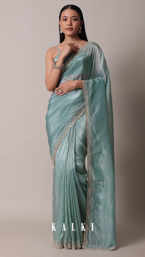 "Introducing our vibrant and stylish saree that helps you exude an opulent charm. Crafted in a vivid blue hue, it is tailored from rich tissue sil fabric. Elevated with dainty mirror work on the border, it showcases a scallop cutwork border and stone studded embellishments. Completed with an unstitched blouse piece, this drape will earn you a ton of compliments. 
" Pastel Net Saree, Teal Saree With Contrast Blouse, Dusty Blue Saree, Turquoise Indian Outfit, Western Saree Draping, Blue Tissue Saree, Kalki Saree, Saree Styles Modern Classy, Grad Saree