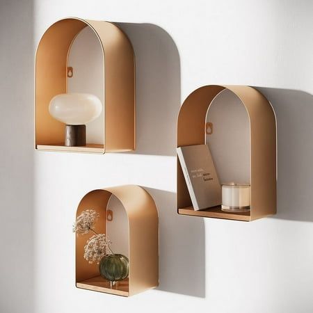 Transform your living area or office with the Aurelia Gold Arch Metal Modern Wall Shelf Set of 3. Each arch-shaped floating shelf in this set is progressively larger than the last, offering ample shelving space for showcasing your favorite items. Bathed in a radiant gold finish, these shelves double as an opulent form of wall dcor that adds a layer of warmth and luxury to any environment. The Aurelia Gold Shelf Set is as functional as it is elegant, making it ideal for displaying decorative pieces or treasured keepsakes. Whether grouped in a single space or separated to adorn multiple areas, these versatile shelves perfectly blend aesthetic appeal and practicality. Size: 15.5" H x 10.5" W x 5" D. Art Deco Bedroom Decor, Mid Century Shelf, Display Shelf Design, Small Bathroom Shelves, Metal Floating Shelves, Gold Shelves, Rustic Wall Shelves, Floating Shelf Decor, Modern Wall Shelf