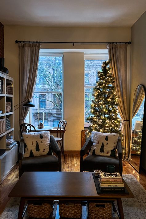 cozy warmly lit apartment, photo facing open window with brownstone view. lit Christmas tree, green chairs, holiday theme Apartment Aesthetic Nyc, Nyc Apartment Modern, Aesthetic Nyc Apartment, Winter Apartment, Nyc Apartment Aesthetic, Cozy Apartment Aesthetic, Apartment Cozy, Apartment New York, Nyc Holidays