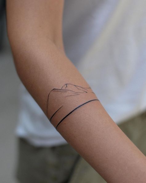 20 Mountain Tattoo Ideas That Prove The Power Of Simplicity Band Mountain Tattoo, Arm Band Mountain Tattoo, Mountain Back Of Arm Tattoo, Matching Tattoos Couples Nature, Mountain Wrap Tattoo, Mountain Tattoo Arm Band, Bc Tattoo Ideas, Topo Lines Tattoo, One Line Tattoo Mountain