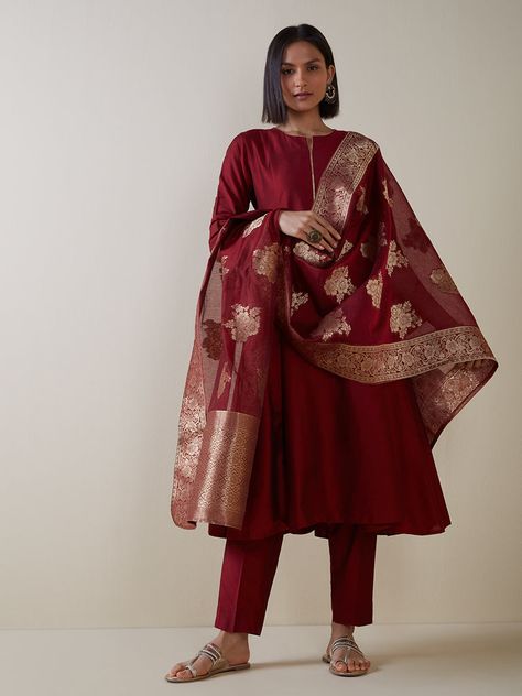 This maroon set is the ultimate symbol of enduring elegance. Woven from a lightweight fabric, the kurta is crafted in a fit-and-flare style and is imbued with a gold trim neckline for a touch of elegance. It also comes with pants and a benarasi-printed dupatta for a striking finish. SPECIFICATION: Colour - Maroon Fabric - Viscose Top type - Kurta Top Shape - Anarkali Top Print - Solid Sleeves - 3/4Sleeves Bottom Type - Pants Bottom Hemline - Straight Bottom Pattern - Solid Dupatta Fabric - Banar Banarsi Dupatta Suits, Maroon Anarkali, Banarsi Suit, Banarsi Dupatta, Colour Aesthetic, Anarkali Tops, Maroon Suit, Maroon Fabric, Kurta Top