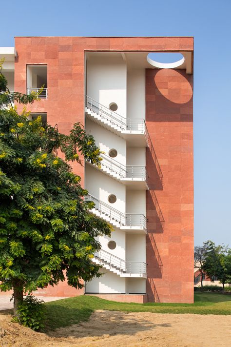 The taller block of Vidya Devi Jindal Paramedical College is clad in red sandstone. Indian Architecture, University Architecture, College Building, Black Brick Wall, External Staircase, College Architecture, Red Sandstone, Brick Building, Facade Design