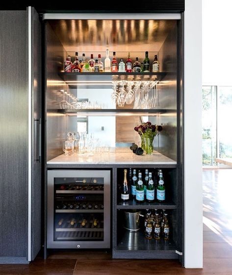 If you plan on adding in many new appliances or lighting when renovating, it may mean your home needs to be rewired. Cool bar set up with drinks fridge, wine fridge, pocket door, mirrored splashback, marble benchtop, charcoal veneer shelving, backlights Home Bar Ideas Living Room, Wine Fridge Cabinet, Mini Bar At Home, Kitchen Bar Design, Closet Bar, Kitchen Design Gallery, Home Bar Cabinet, Home Bar Rooms, Modern Home Bar