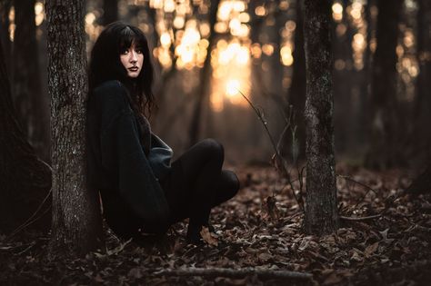 a goth high school senior leans against a tree in the woods at sunset for moody senior photos Gothic Senior Pictures Photo Shoot, Moody Senior Portraits, Horror Senior Pictures, Moody Senior Photos, Goth Senior Picture Ideas, Dark Academia Senior Pictures, Goth Senior Photos, Spooky Senior Pictures, Dark Senior Pictures