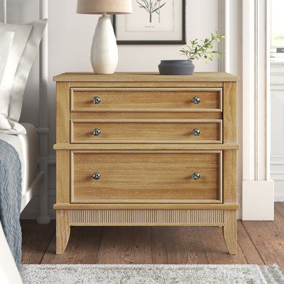 This 3-drawer nightstand is just what you need to keep your favorite reads and devices all within reach from your bed. It's made from solid pine wood, and has tapered legs and a slatted pattern on the bottom with a rustic natural wood finish for tons of French country charm. Three drawers with wooden inlays on the fronts glide open to hold essential items like reading glasses, hand lotions, and remotes. Plus, we love that the surface is perfect for holding a small lamp or a photo of friends and Coastal Dresser And Nightstand, Boho Farmhouse Nightstand, Wide Nightstands, Dresser Nightstand Ideas, Natural Wood Bedroom Furniture, Natural Wood Nightstand, Light Wood Nightstand, Photo Of Friends, Small Nightstand Lamps