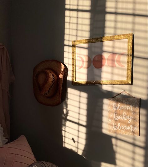 sunlight filters on a collage wall with a picture frame and a cowboy hat in the collage Cowboy Hat On Wall, Cowboy Hat Wall Decor, Hat Hanging Ideas, Cowboy Hat Display, Cowboy Hat Wall, Hat Wall Decor, Holiday Bedroom, Hat Wall, Hanging Hats