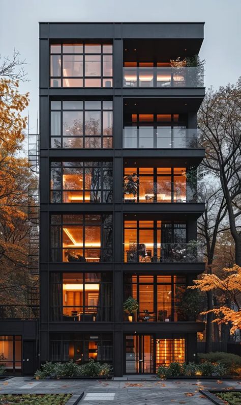 The image is of a modern apartment building with a black exterior and large windows. The building is surrounded by trees with orange autumn leaves ->> more details in ai-img-gen.com Loft Apartment Building Exterior, Fancy Apartment Building Exterior, Tall House Design, Cute Apartment Exterior, High Rise Apartment Exterior, Small Apartment Exterior, Apartment Building Aesthetic, 4 Storey Building Elevation, Apartment Complex Exterior