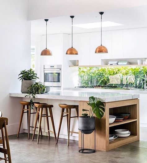 white kitchen, cement floors, copper pendant lighting, white countertops, green plants, wood barstools Island Shelf, Kitchen With An Island, Hus Inspiration, Kitchen Taps, Trendy Kitchen, Steel Kitchen, Project Design, House And Home Magazine, Küchen Design