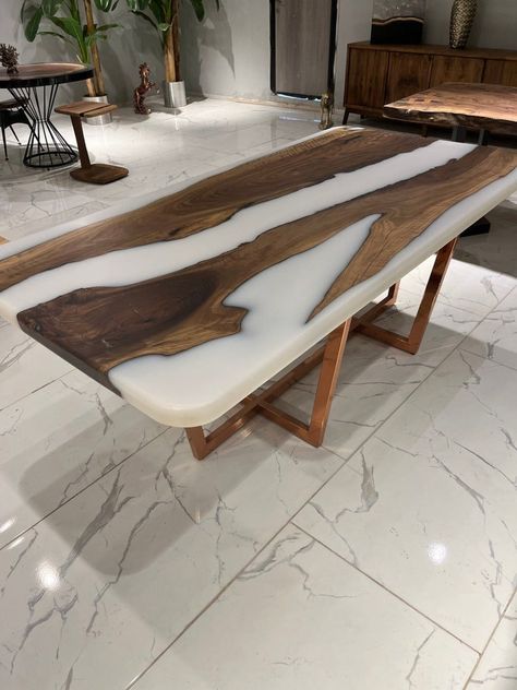 Discover the beauty of our custom epoxy table, a unique blend of nature and craftsmanship. This exquisite piece of furniture is not just a table, but a work of art that adds a touch of elegance and sophistication to any room. Each epoxy table is handcrafted with meticulous attention to detail, ensuring that no two tables are exactly alike. The live edge table design encapsulates the raw beauty of nature, making it a conversation starter in your living room or dining area. Our epoxy coffee table Epoxy Dinning Table, Unique Dining Table Design, Epoxy Dining Room Table, White Epoxy Table, Wood Epoxy Table, Epoxy Resin Dining Table, Dining Table Epoxy, Resin Dining Table, Epoxy Dining Table