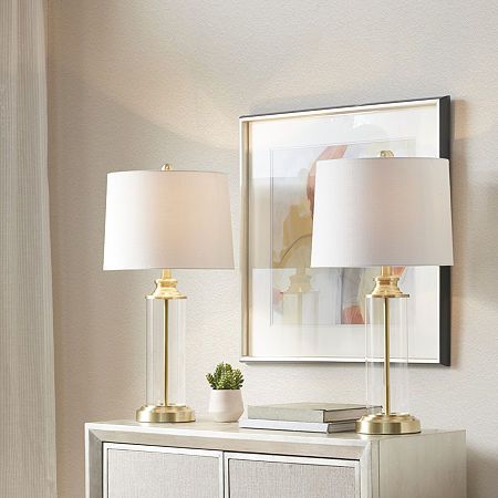 Update your living room or bedroom with the sleek style of the clarity table lamp set of two. The base is made from metal and glass with a gold finish, for an elegant touch. An off-white drum-shaped shade softly filters the light, while also beautifully complementing the striking look. Providing plenty of length a 72-inch clear cord and an on/off switch on the socket, this table lamp is easy to incorporate into your existing space and perfect for accenting any transitional home decor. One type … Clear Table Lamp, Silver Table Lamps, Table Lamp Set, Transitional Home Decor, Pc Table, Silver Table, Gold Lamp, Glass Cylinder, Gold Table Lamp